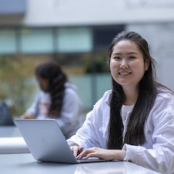 Female student smiling and with hands on laptop 