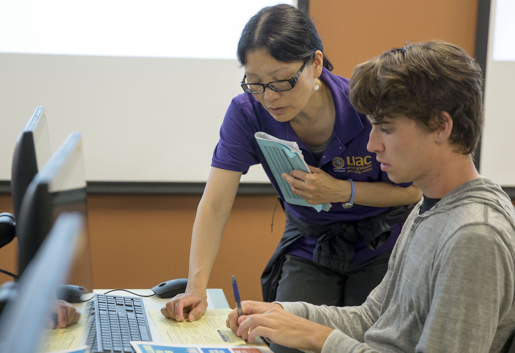 student and advisor looking at computer and papers on desk