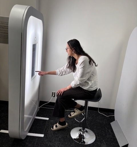 SFSU student seated on a tall stool and using Iris photo booth for professional headshot