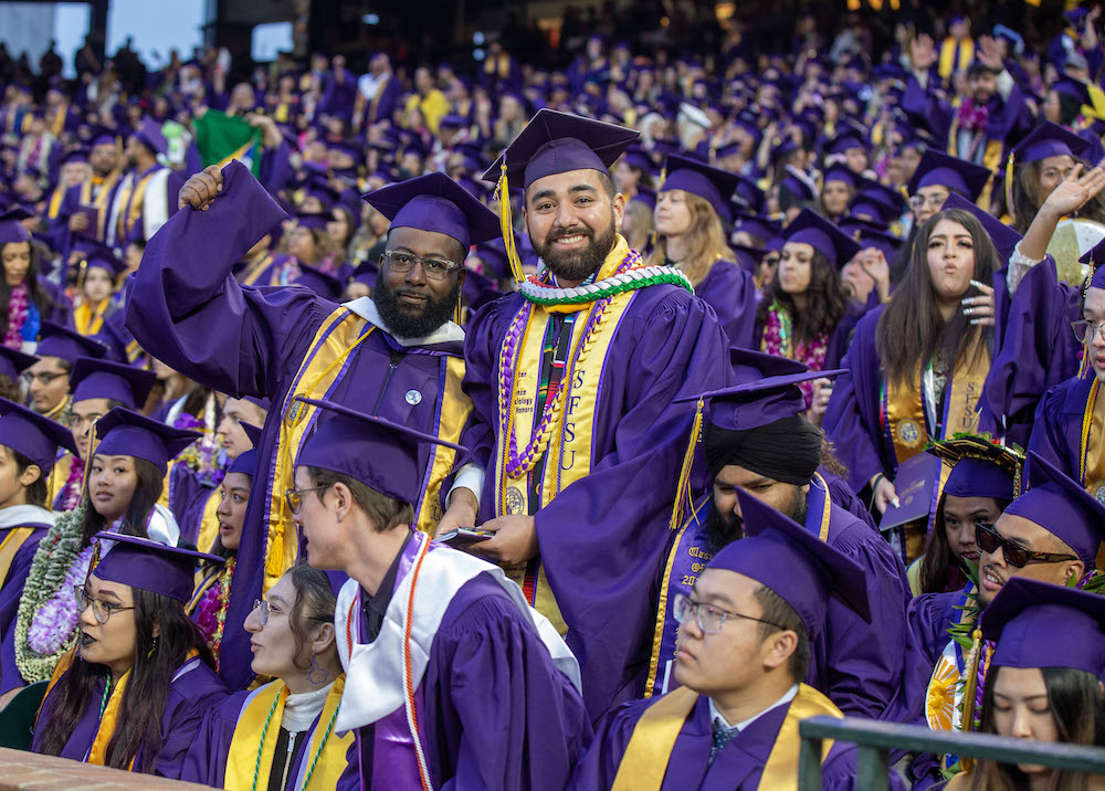 SFSU Commencement at Giants Stadium in SF, two male students standing up and celebrating 