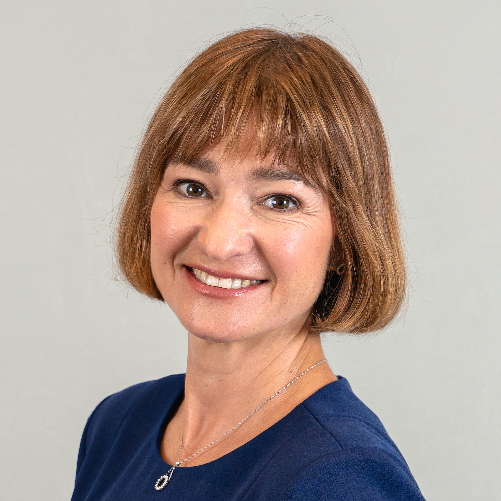 Headshot of smiling woman with short light brown wearing a blue top or dress