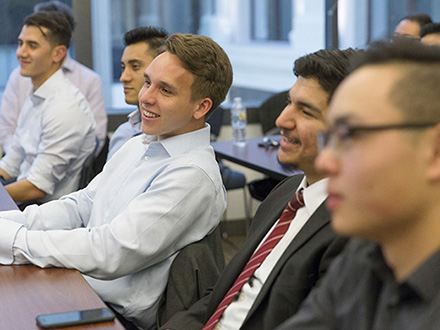 A group of students sitting at a table in a conference room.