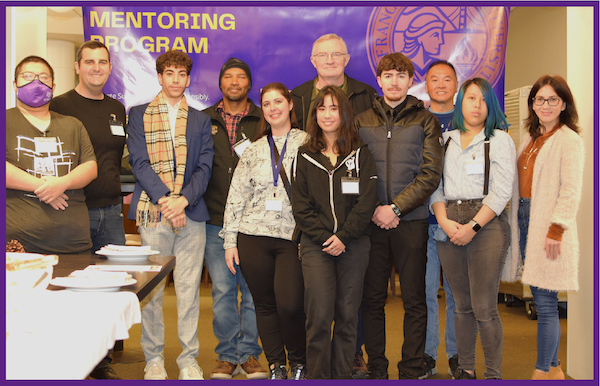 Mentorship program students and alumni standing in front of backdrop with program name
