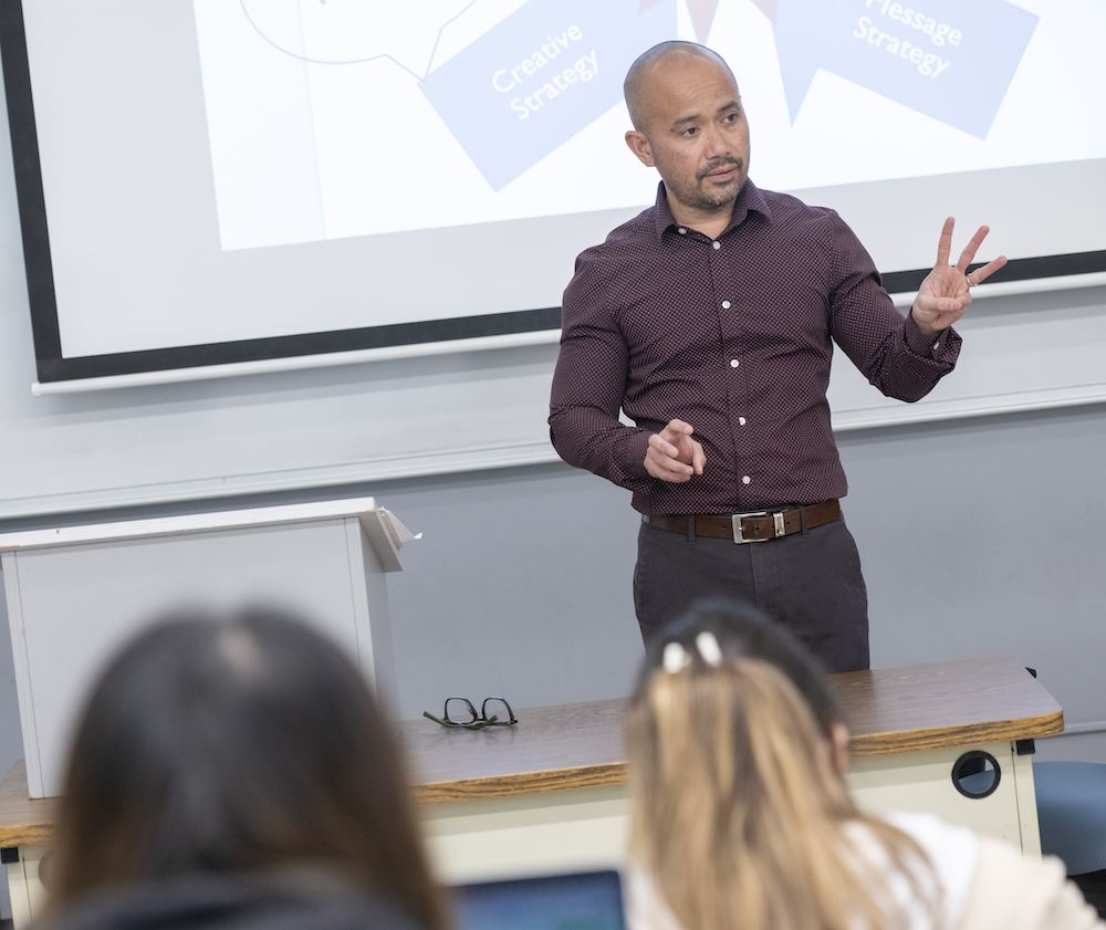 LFCOB Marketing Professor Ian Sinapuelas teaching students in classroom, in March 2023