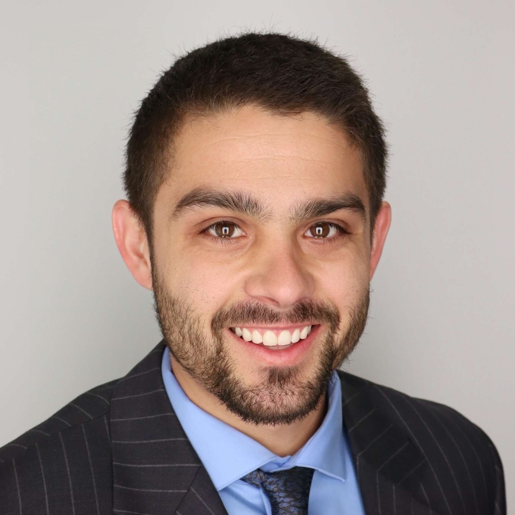 Neil Sterud, MBA student, man with short dark hair, light beard and mustache, wearing suit jacket, light blue shirt and dark tie