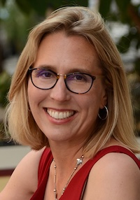 SFSU Professor Susan Cholette, headshot of smiling woman with short blonde hair, wearing dark-rimmed glasses and red sleeveless top