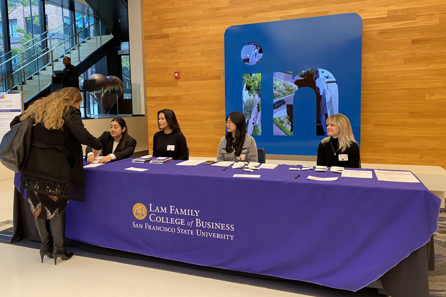 WELF 2024 (3): registration table with 4 staff and LinkedIn sign in the background