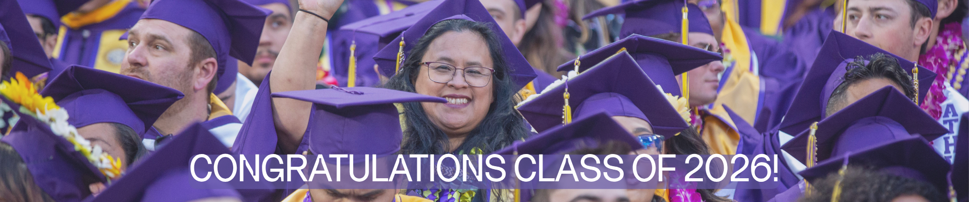 Smiling graduating students wearing caps and gowns at commencement