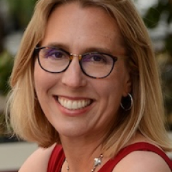 SFSU Professor Susan Cholette, headshot of smiling woman with short blonde hair, wearing dark-rimmed glasses and red sleeveless top